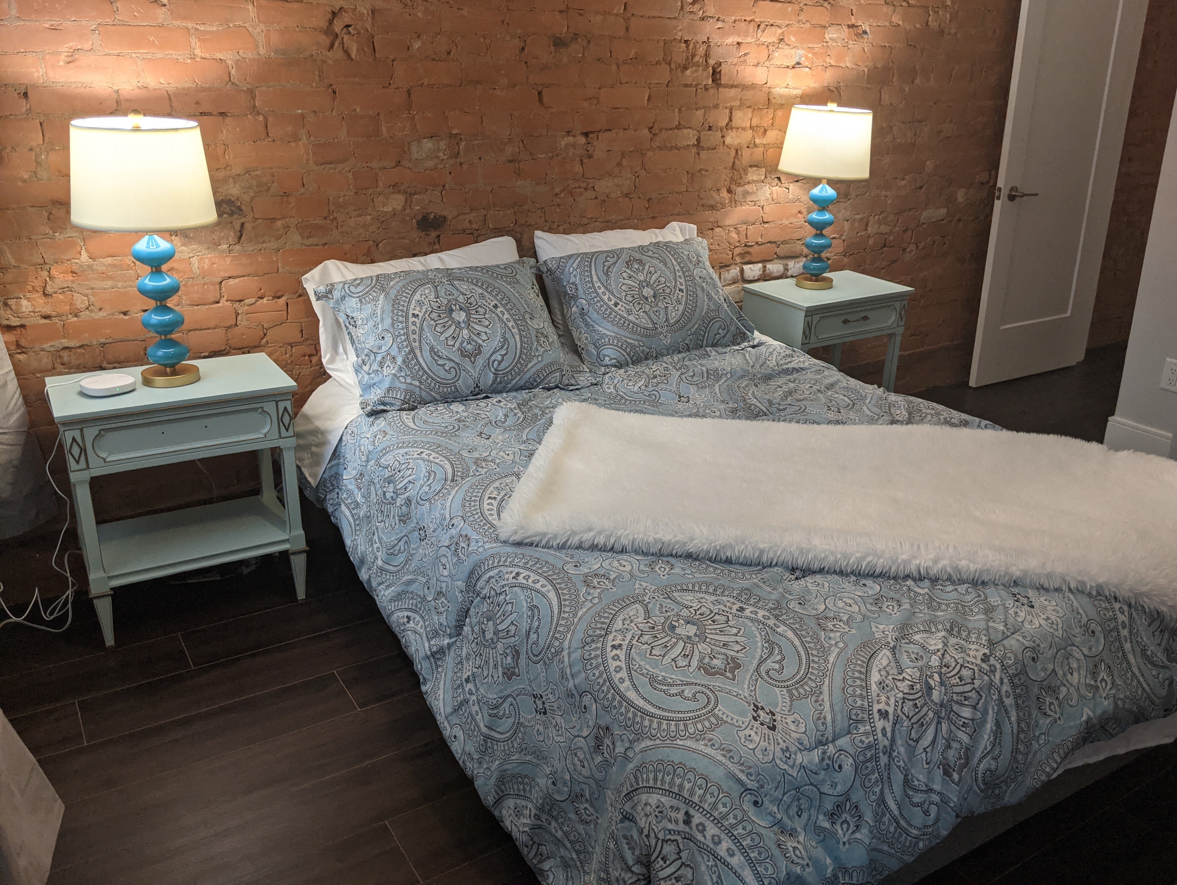 a bedroom with a bed and two lamps and a brick wall